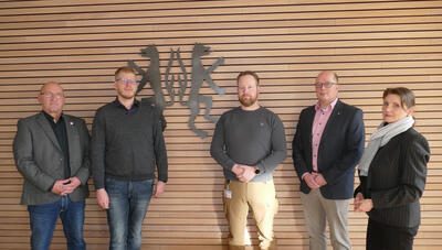 Bild vergrößern: Vier Mnner und eine Frau stehen in einem Sitzungsraum vor einer vertfelten Wand, die das Kreiswappen zeigt. Alle Personen blicken in die Kamera.