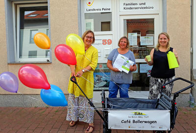 Bild vergrößern: Drei Frau stehen mit Luftballons in der Hand hinter einem Bollerwagen.