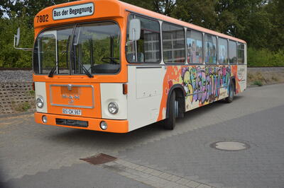 Bild vergrößern: Es ist ein orange-weier Bus zu sehen, der an der Seite bunt mit den Worten "Bus der Begegnung" bemalt ist. Im hinteren Bereich des Busses sieht man das Logo "Lokales Bndnis fr Familie im Landkreis Peine".