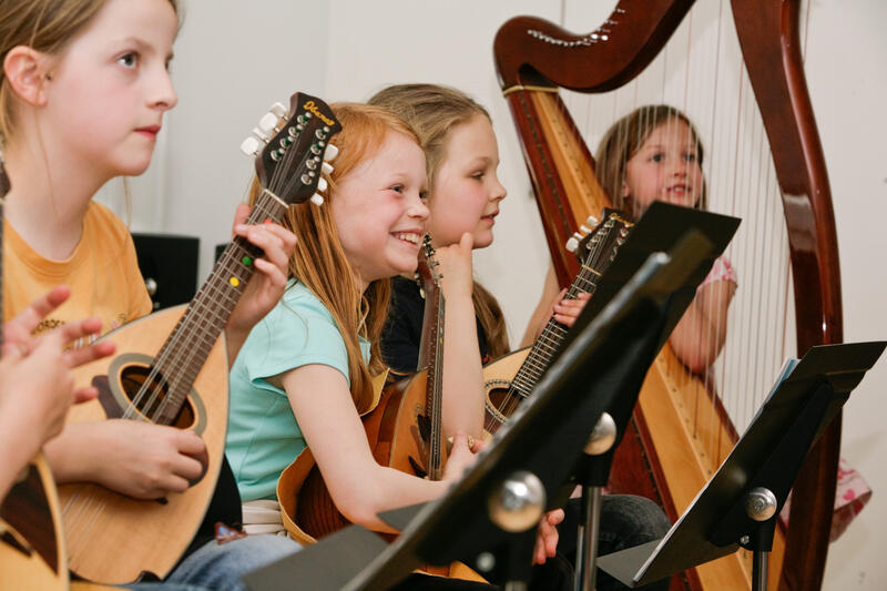 Vier Mädchen sitzen an Notenständern und halten verschiedene Instrumente in den Händen.