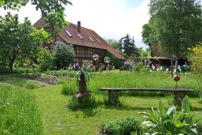 Bild vergrößern: Das Bild zeigt einen Garten im Frhling mit einer Bank im Vordergrund. Im Hintergrund ist ein groes Fachwerkhaus zu erkennen.