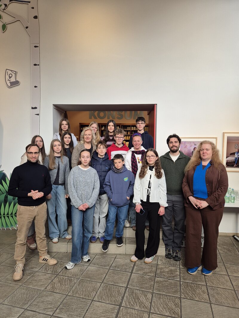 Das Bild zeigt zw&ouml;lf Jugendliche sowie zwei M&auml;nner und drei Frauen, die gestaffelt auf den Stufen der Innentreppe des Kreismuseums stehen und in die Kamera blicken.