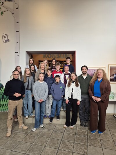 Bild vergr&ouml;&szlig;ern: Das Bild zeigt zw�lf Jugendliche sowie zwei M�nner und drei Frauen, die gestaffelt auf den Stufen der Innentreppe des Kreismuseums stehen und in die Kamera blicken.