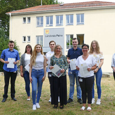 Bild vergrößern: 10 Personen stehen versetzt zueinander drauen auf einer Rasenflche. Im Hintergrund ist der Haupteingang des Kreishauses 1 zu sehen.